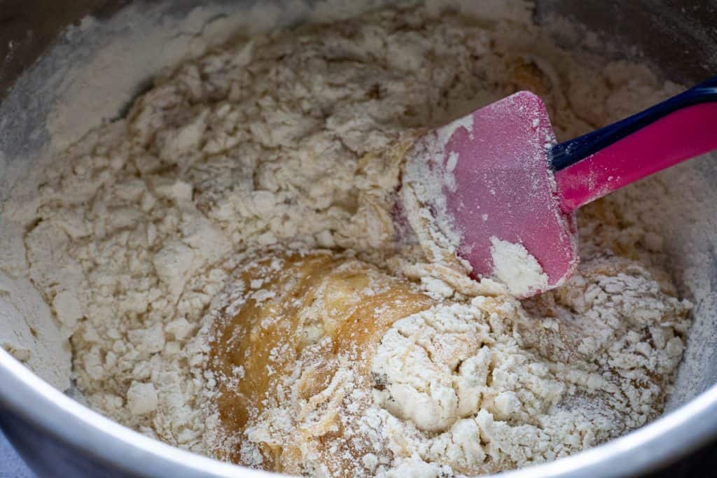 Dry ingredients folded into the sourdough cookie batter with a pink rubber spatula.