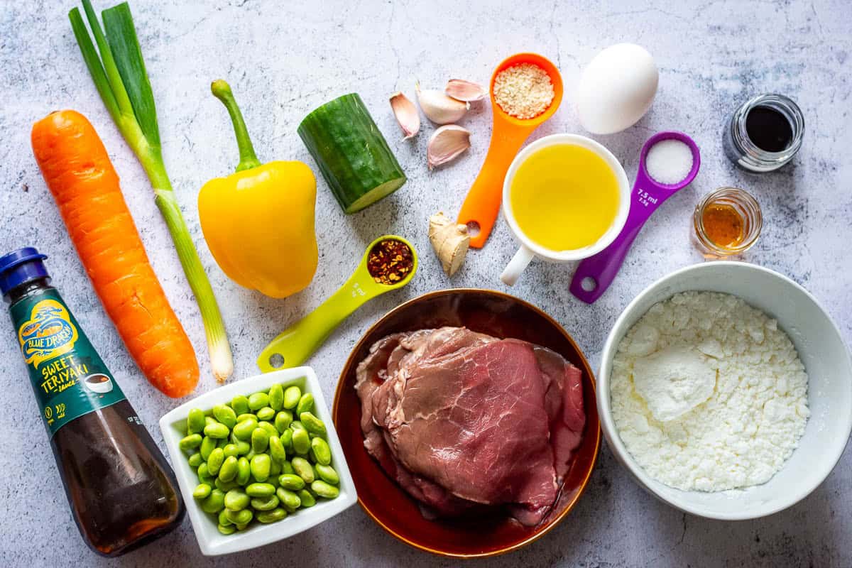 Ingredients for Teriyaki Beef Rice Bowls on a light grey surface.