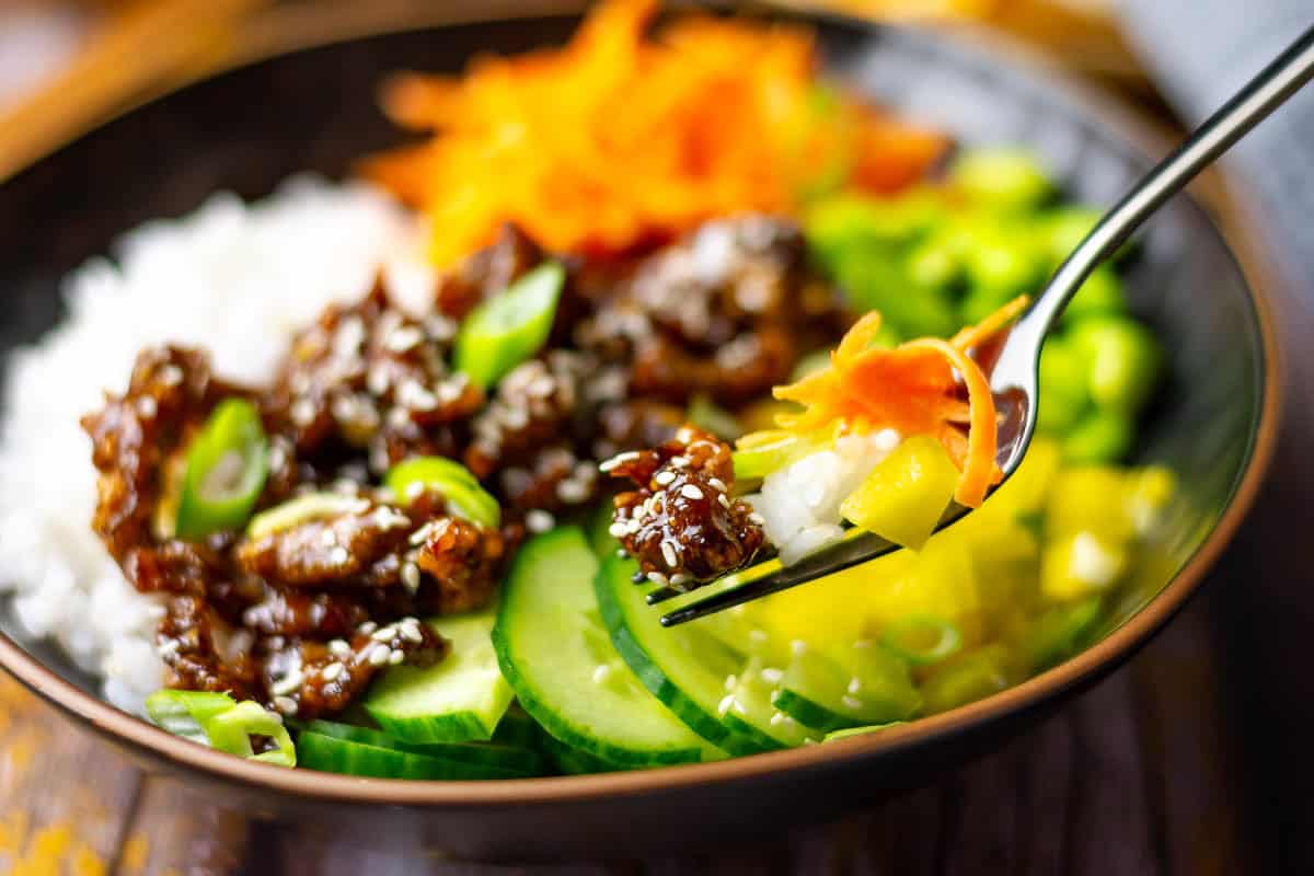 Teriyaki beefrice bowl with a forkful being picked up.