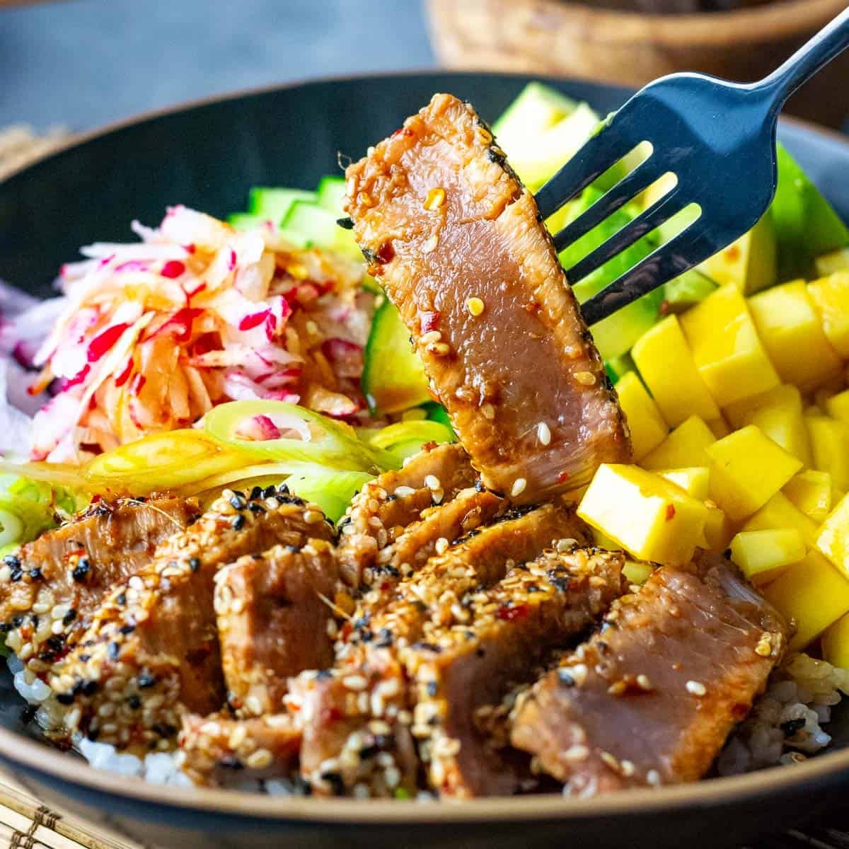 Seared Tuna Poke Bowl with a piece of ahi tuna being picked up form the bowl.