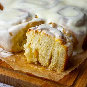 Sourdough Lemon rolls covered in lemon cream cheese icing with one of the sourdough rolls cut in half.