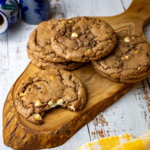 Triple chocolate sourdough cookies with cocoa powder and three types of chocolate chips on a decorative board.