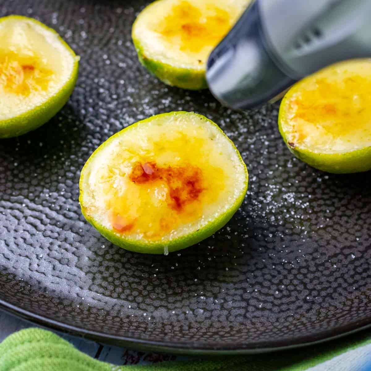 Lime posset in hollowed lime shells being torched with a kitchen blow torch to create caramelised top.