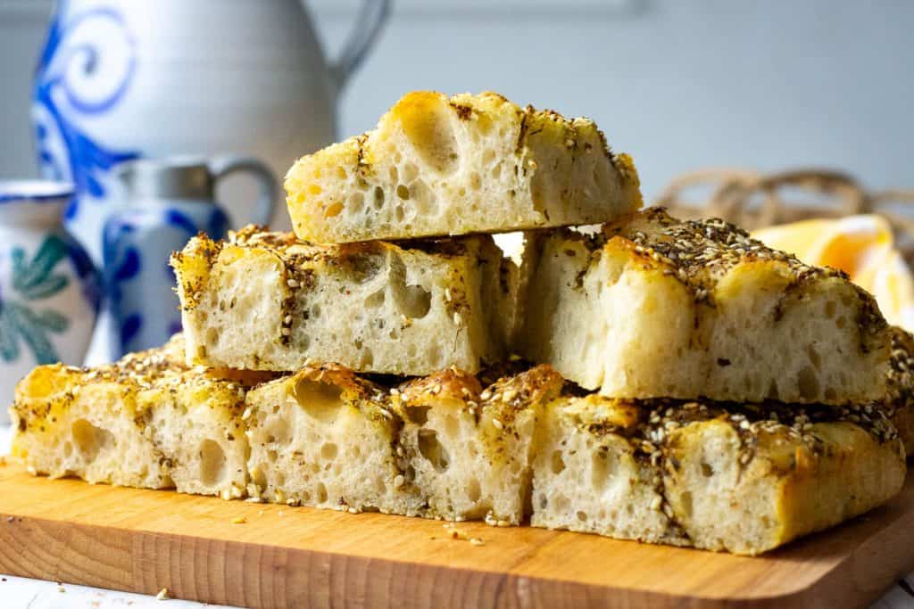 Sliced za'atar sourdough focaccia stacked on a wooden board.