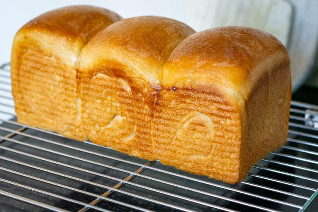 Roll pattern on the side of baked sourdough bread set on a wire rack.