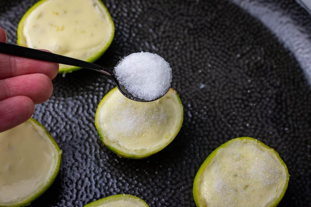 Sprinkling sugar over the lime possets.