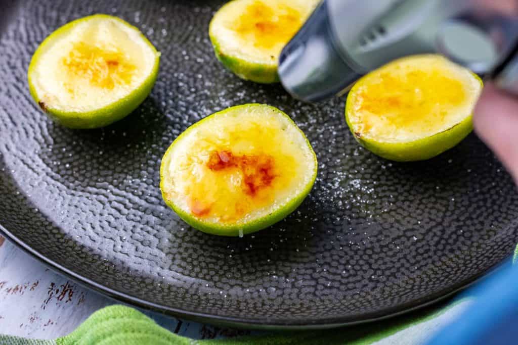 Torching the tops of lime possets to create a hard caramel surface.