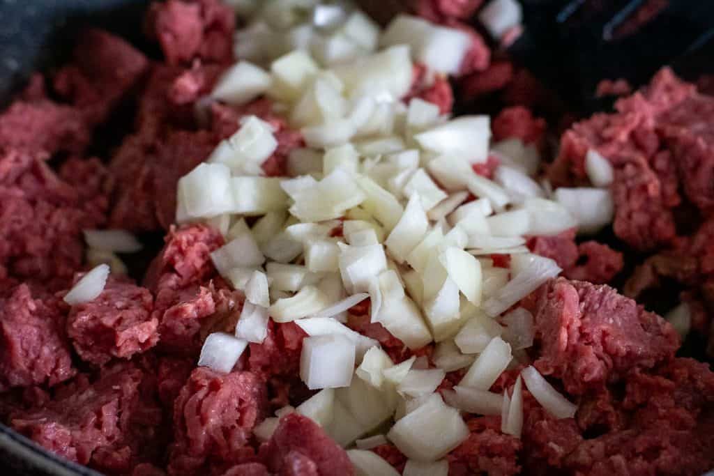Ground beef and onions in a frying pan.