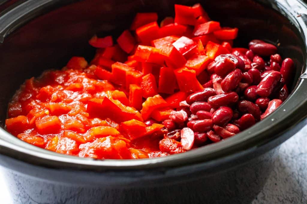 Beans, peppers, tomato paste and chopped tomatoes added to slow cooker alongside the beef.