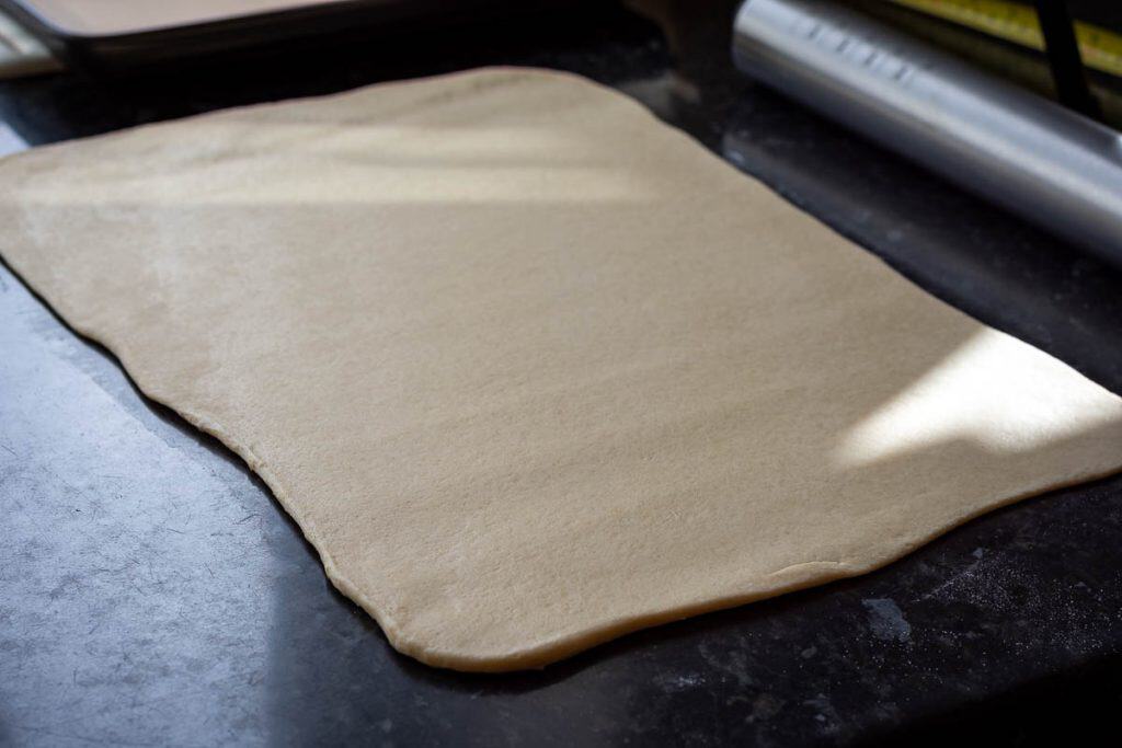 Rolled out sourdough on a kitchen surface.
