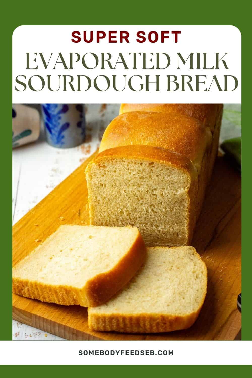 Soft Evaporated Milk Sourdough Sandwich Bread on a wooden board with two slices cut. Pin for Pinterest.