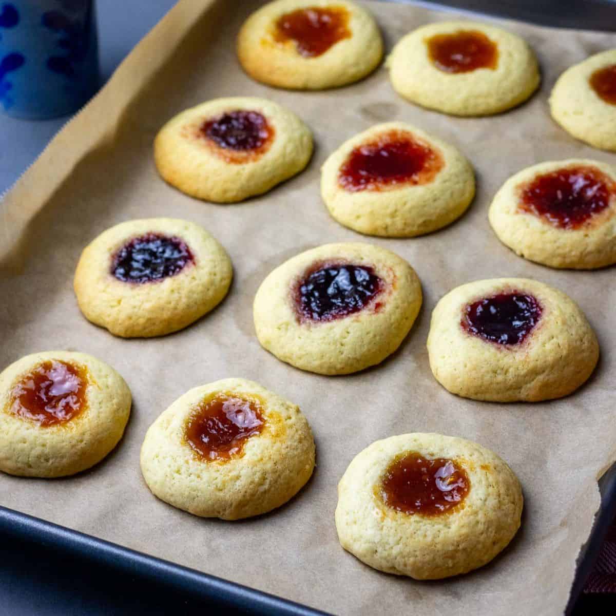 Sourdough Discard Thumbprint Cookies with Jam on a baking sheet lined with parchment paper.