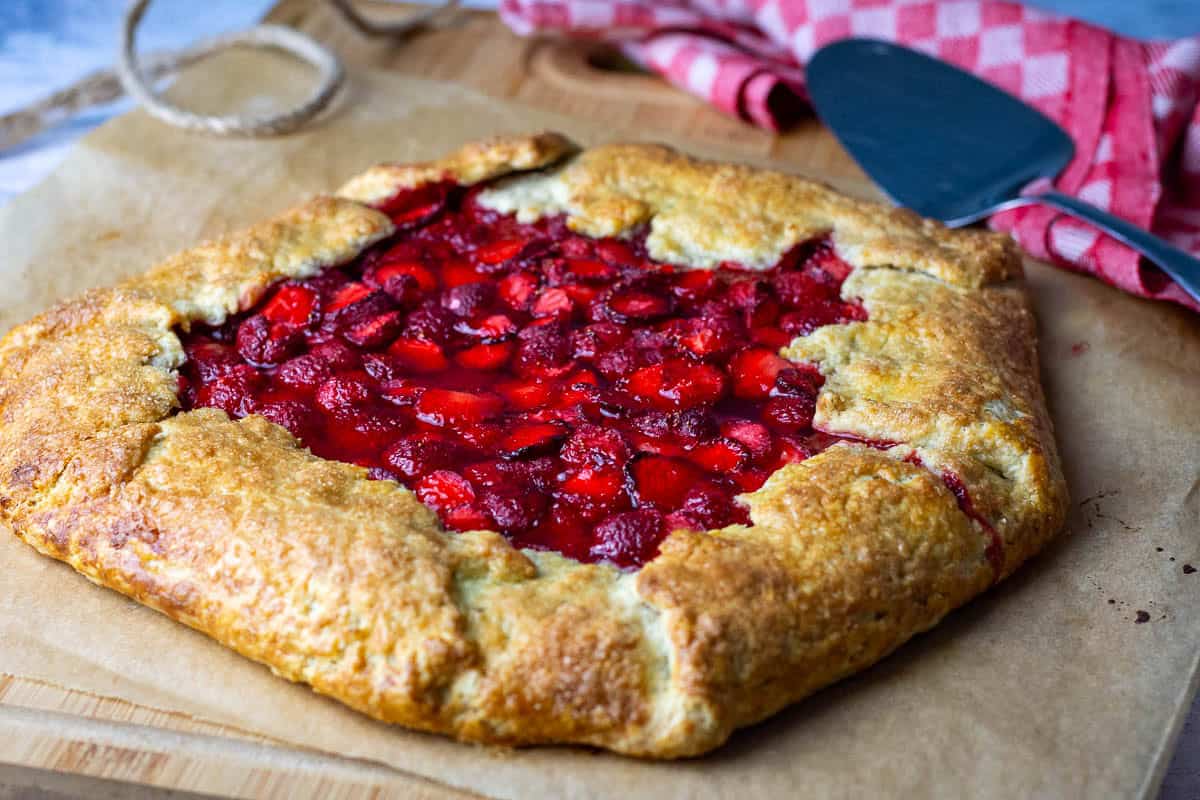 Baked sourdough galette wth strawberries on a wooden board.