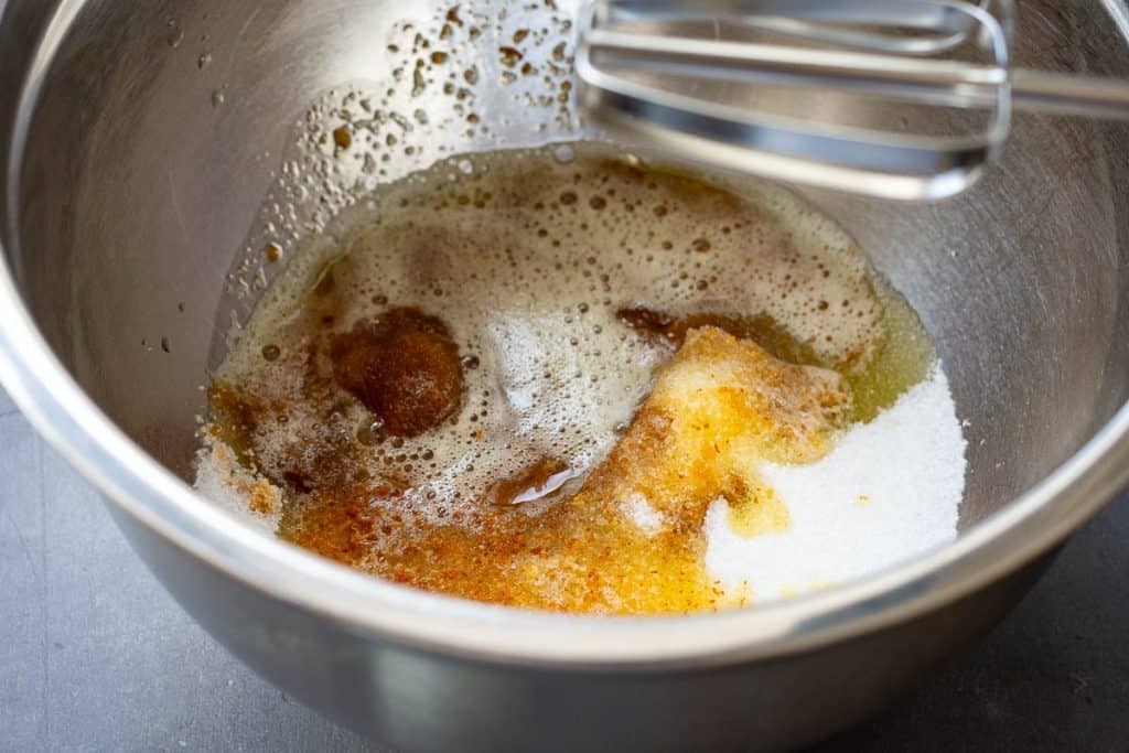 Two types of sugar and browned butter in a large metal mixing bowl.