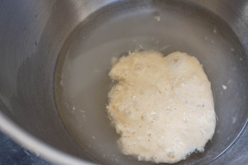 Water and active sourdough starter in a bowl of a stand mixer.