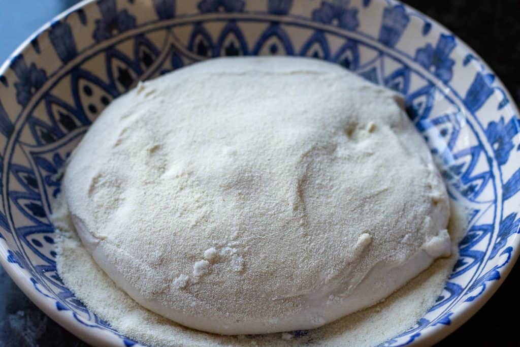 Sourdough pizza dough in a bowl with semolina flour.
