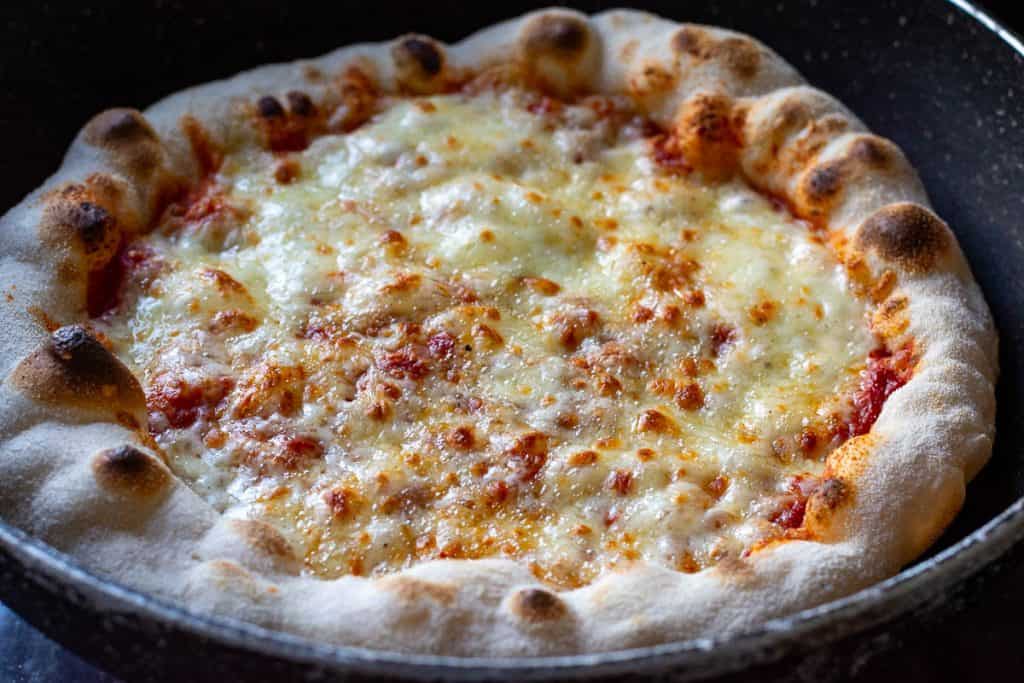 Melted cheese and airy puffy crust on sourdough pizza.