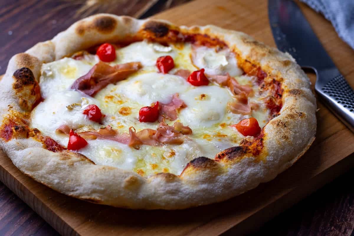 Blistery Neapolitan Style Sourdough Pizza with ham, goat cheese and pearl pepper topping.