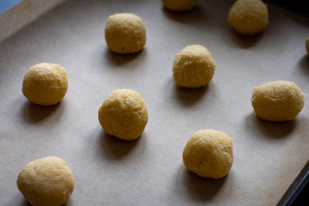 Small balls of sourdough cookie dough on a parchment paper lined tray.