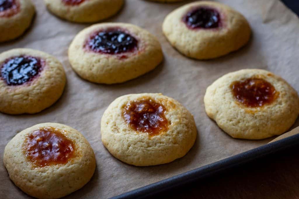 Baked sourdough jam thumbprint cookies on a baking sheet.