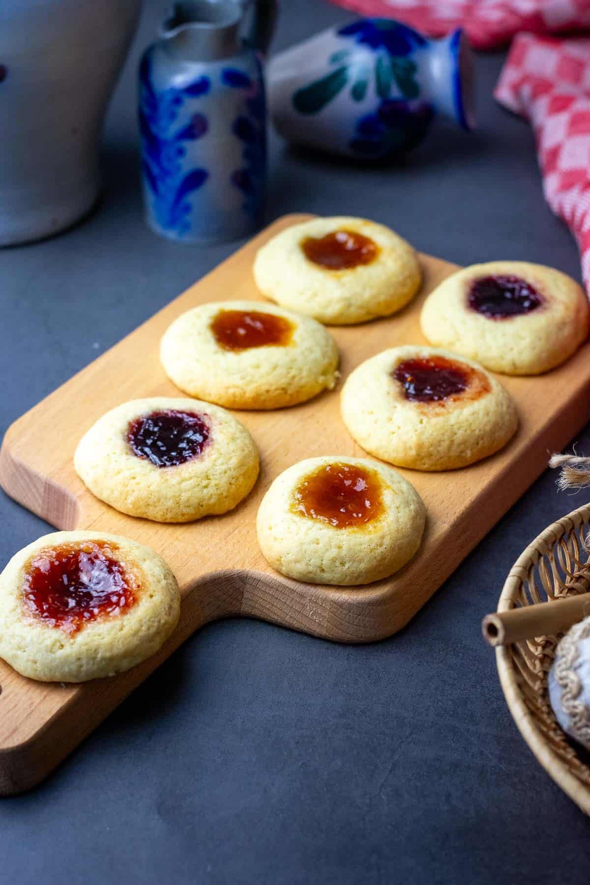 Thumbprint sourdough cookies with jam on a wooden board.