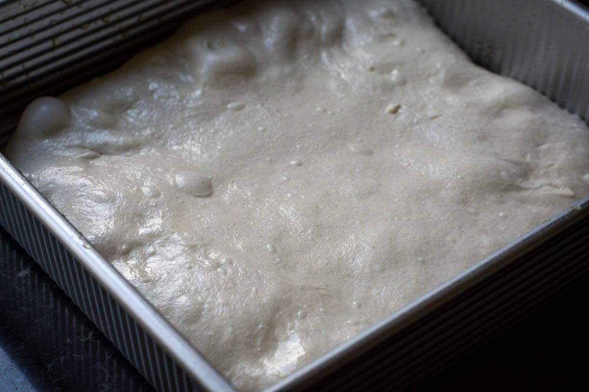 Sourdough focaccia transferred into a baking tray.