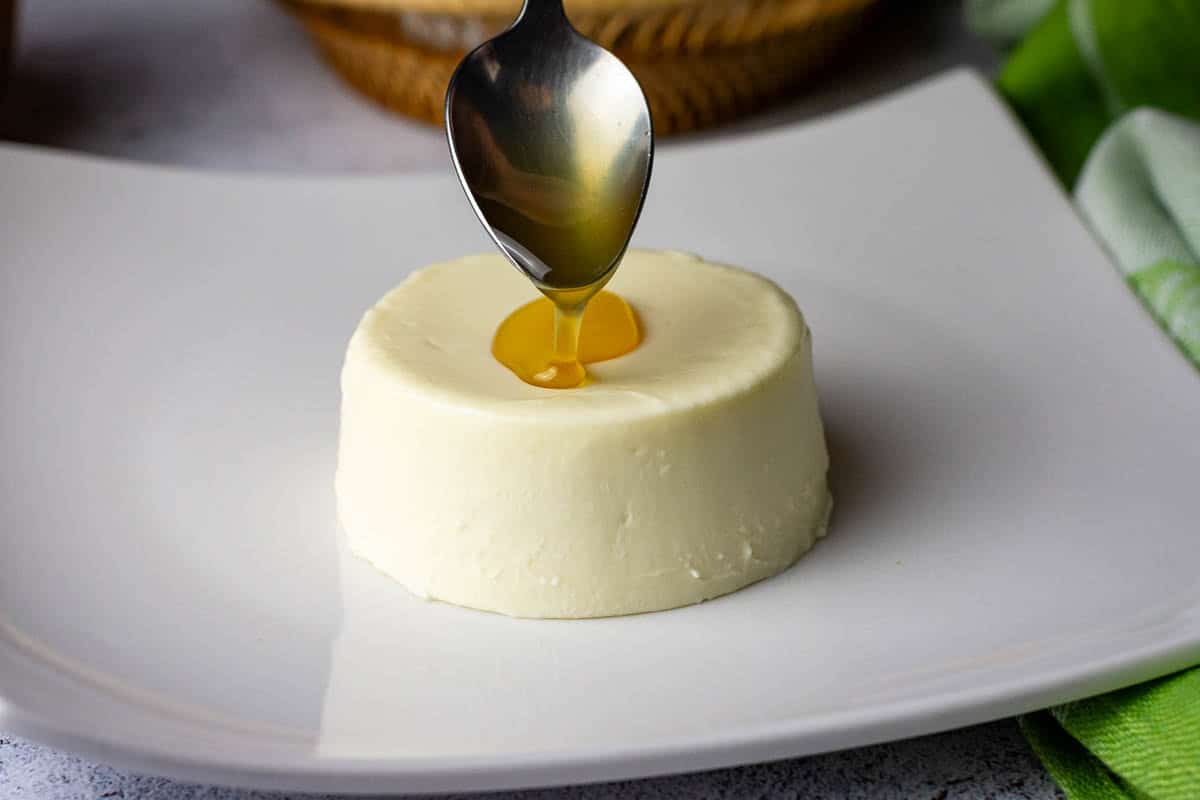 Spooning yuzu syrup over the panna cotta.