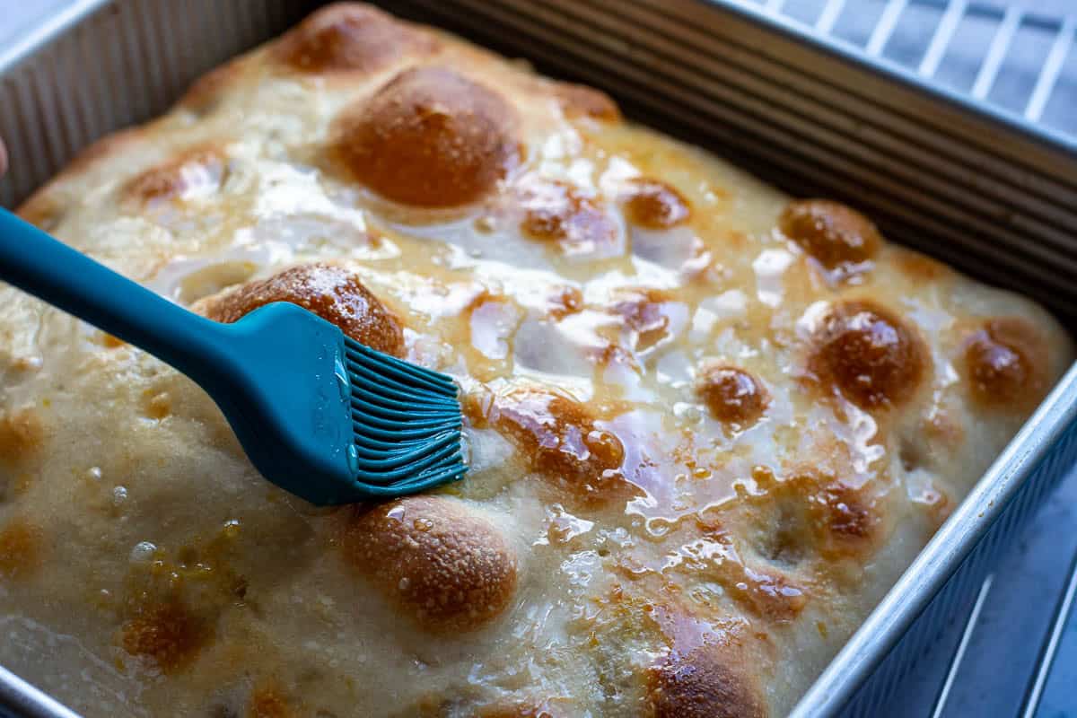 Brushing hot focaccia with lemon syrup.