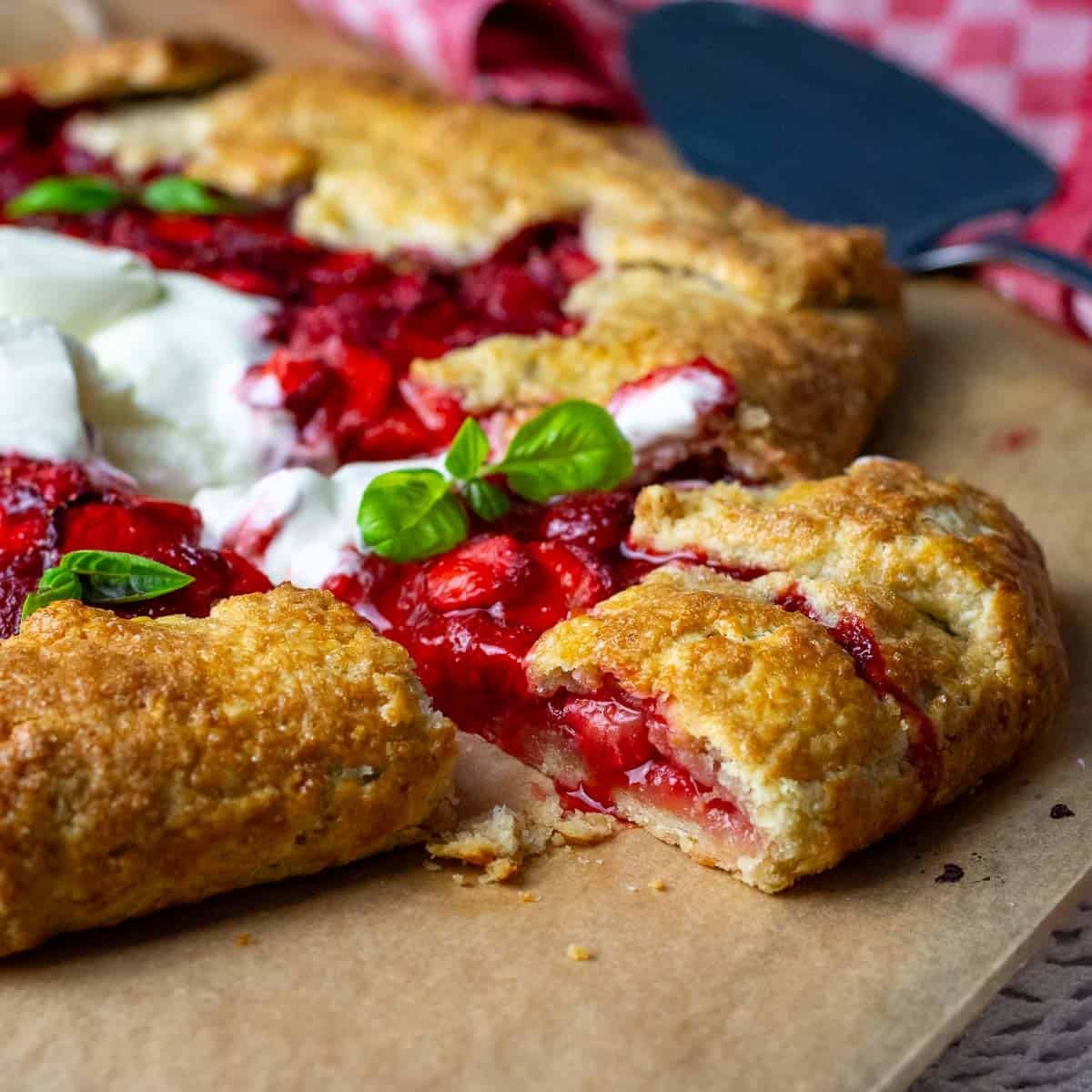 A slice of sourdough galette with fresh strawberries being taken out on a wooden board.