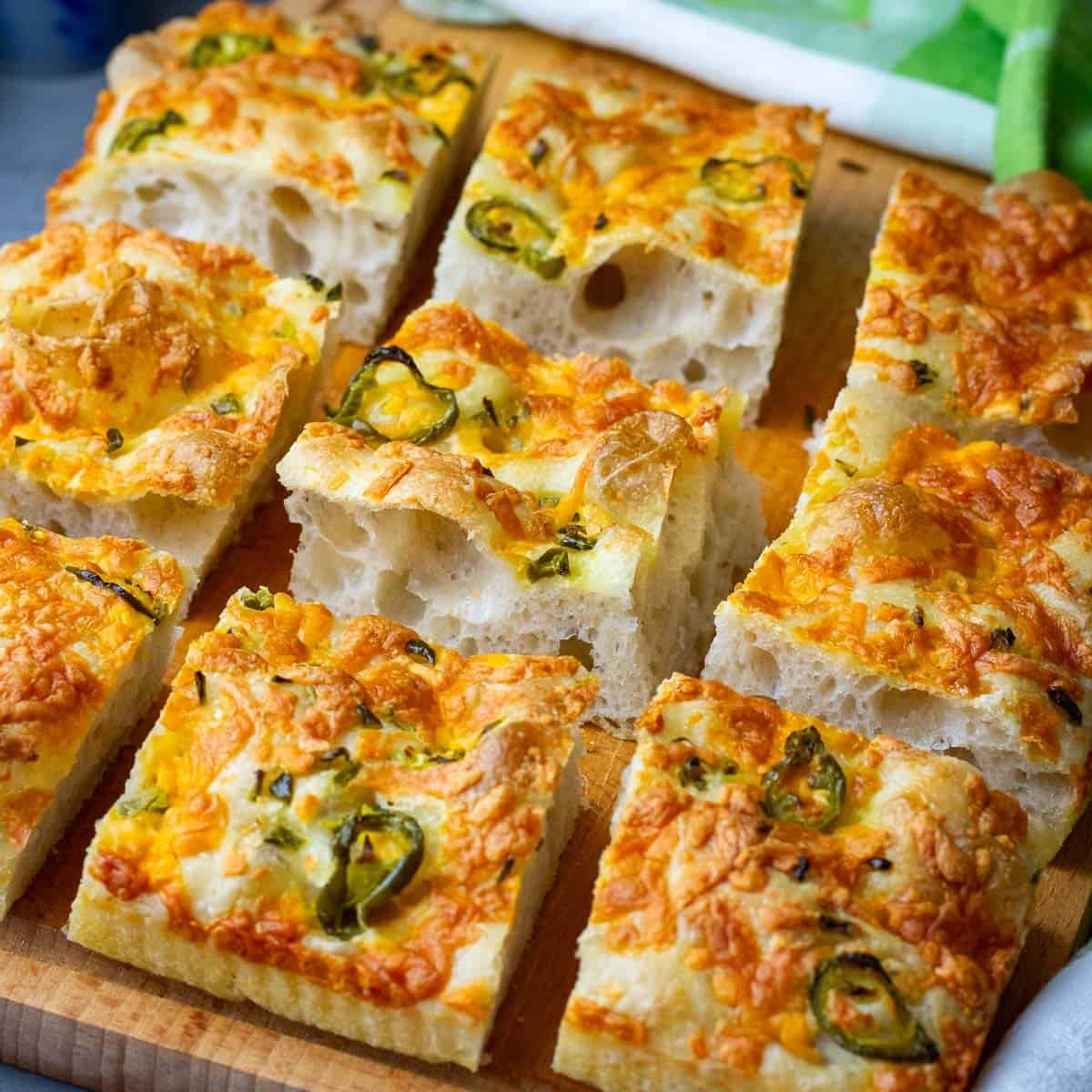 Jalepeno Cheddar Sourdough Focaccia sliced into squares on a wooden cutting board.