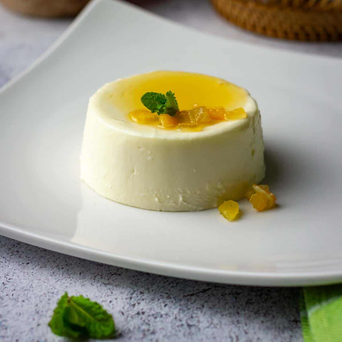 Yuzu panna cotta topped with yuzu syrup and candied peel on a white plate.