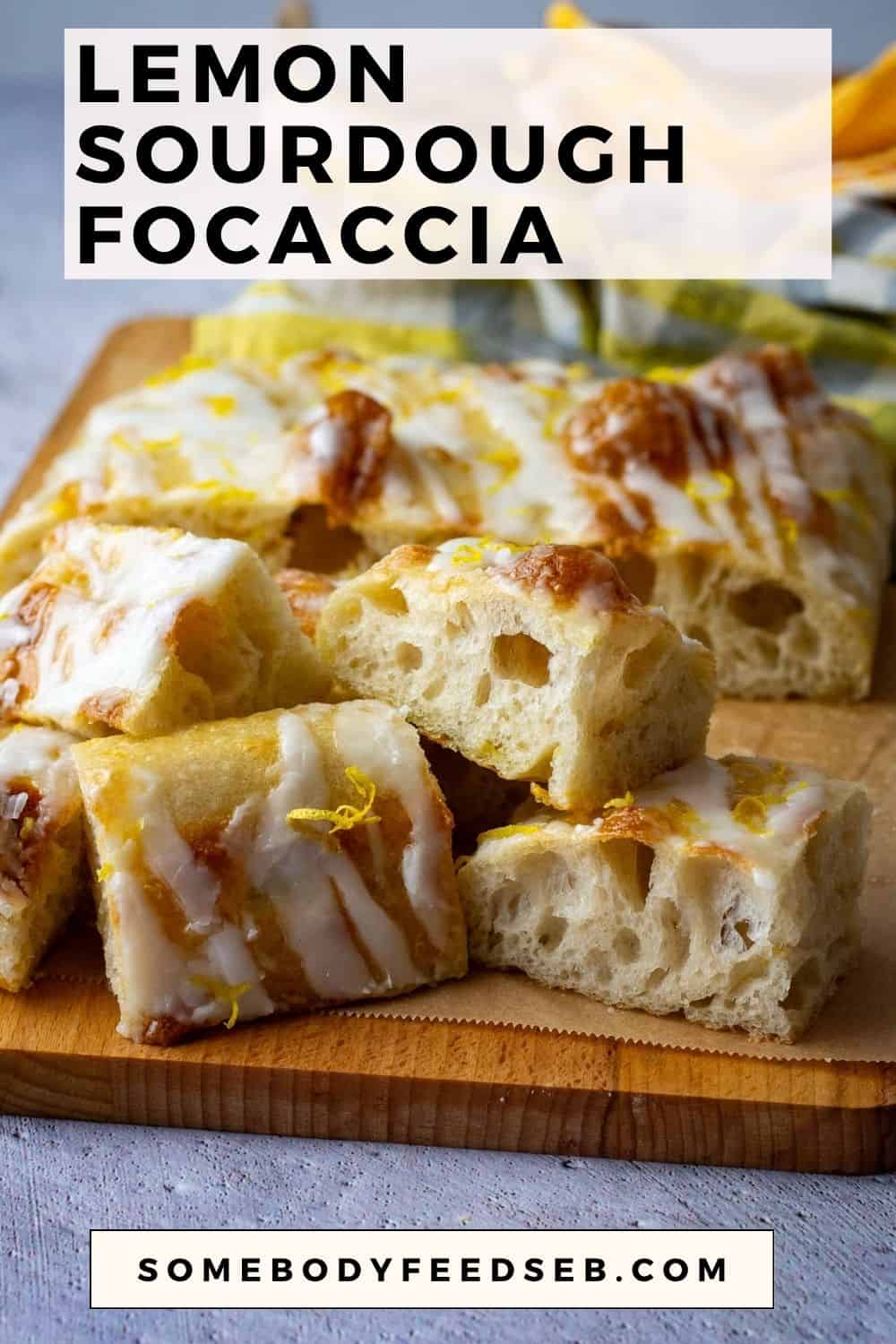 A pile of sliced lemon sourdough focaccia with lemon glaze on a wooden board. Pin for Pinterest.