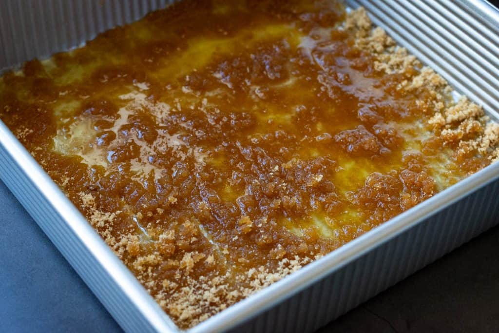 Melted butter and brown sugar on the base of a square baking pan.