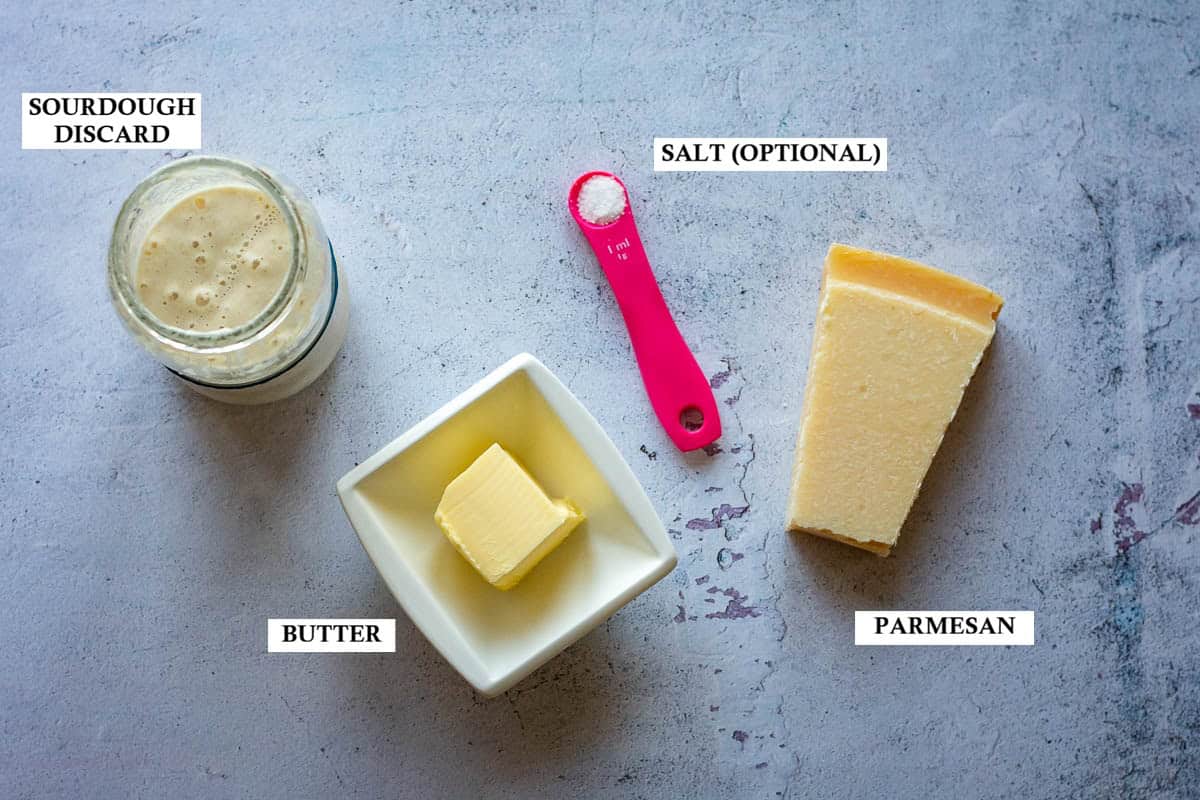 Labelled ingredients for sourdough parmesan crackers on a grey surface.