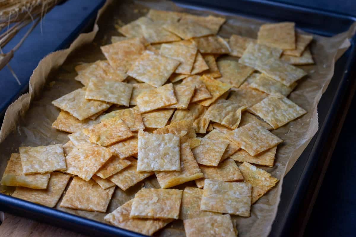 A mound of sourdough discard parmesan crackrs on a baking sheet lined with parchment paper.
