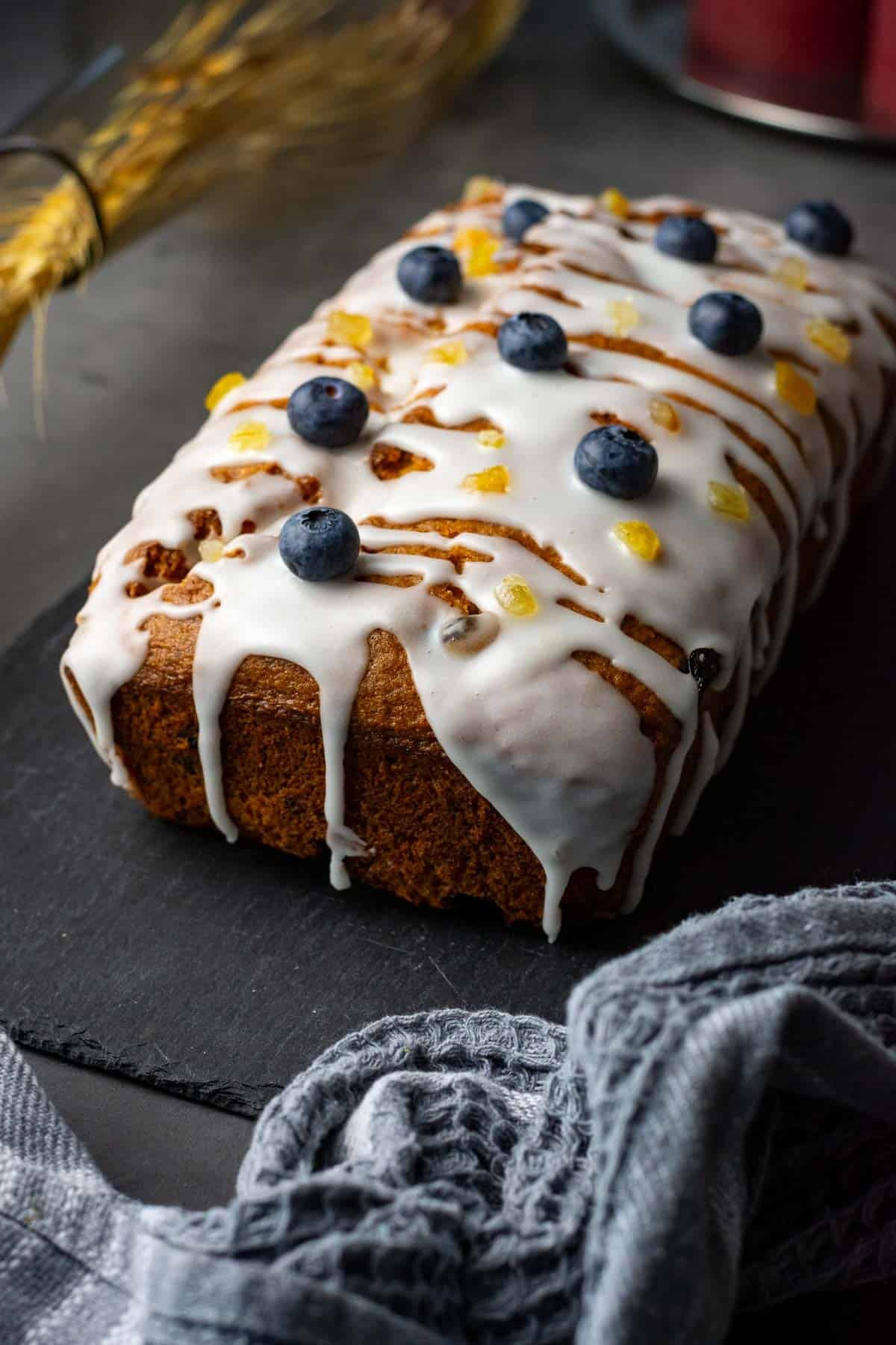 Lemon Blueberry Sourdough Cake glazed with sugar icing and decorated with fresh blueberries and lemon zest.