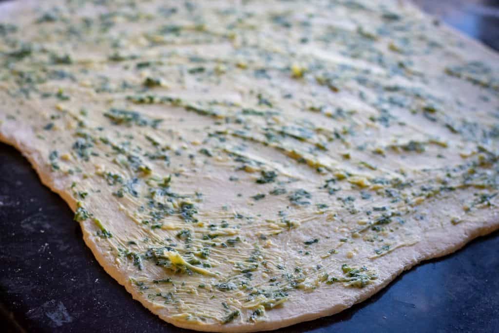 Rolled out sourdough spread with garlic butter mixture.