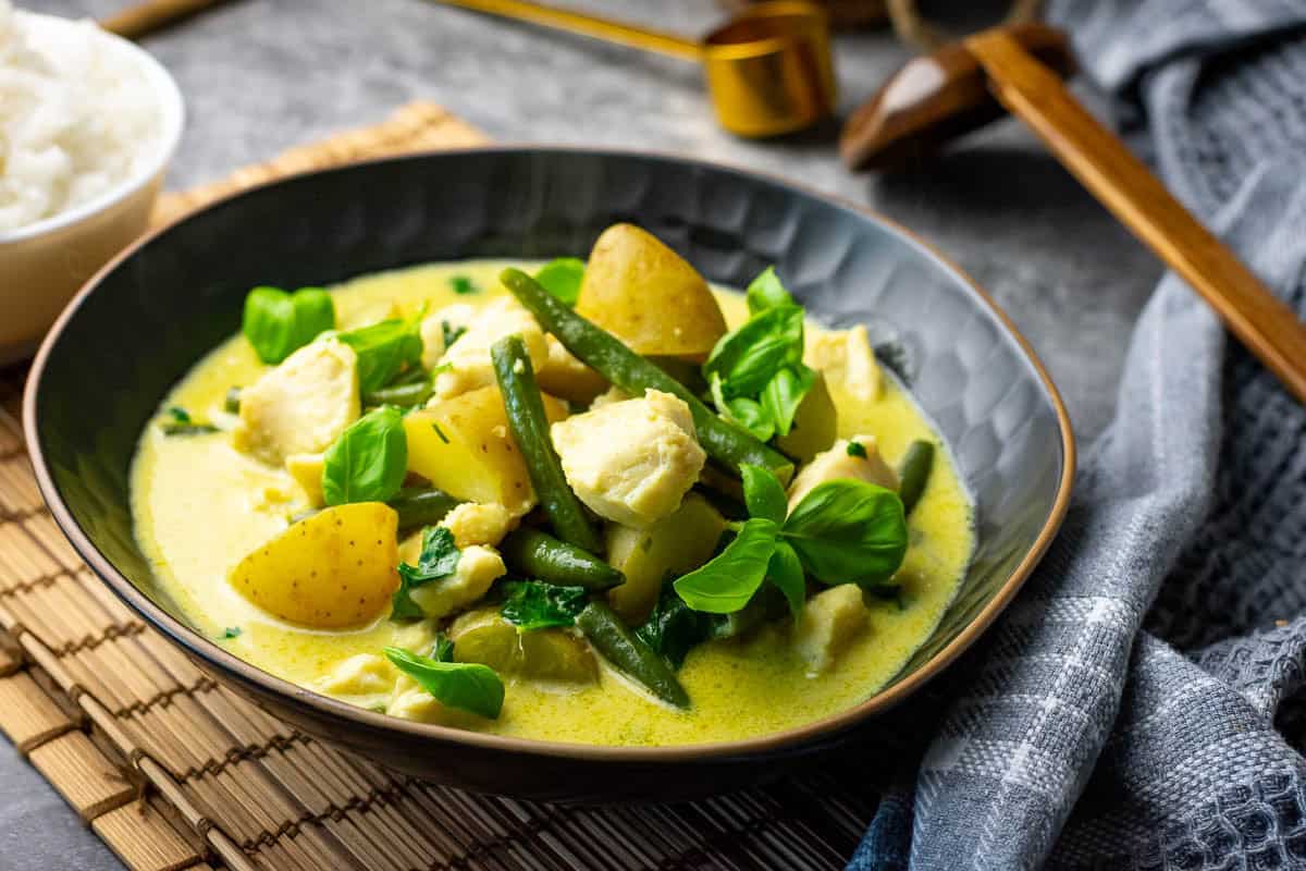 Thai green fish curry in a bowl finished with basil and lime.