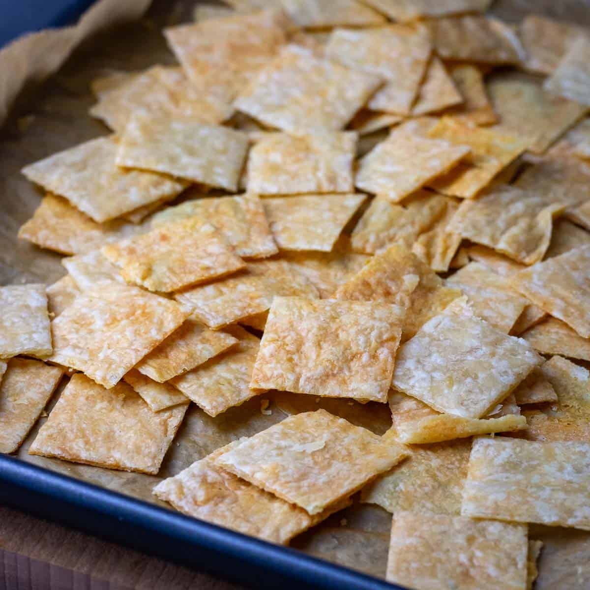 A mound of sourdough discard parmesan crackrs on a baking sheet lined with parchment paper.