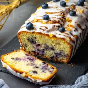 Lemon Blueberry Sourdough Cake on a black slate board with one slice already cut.