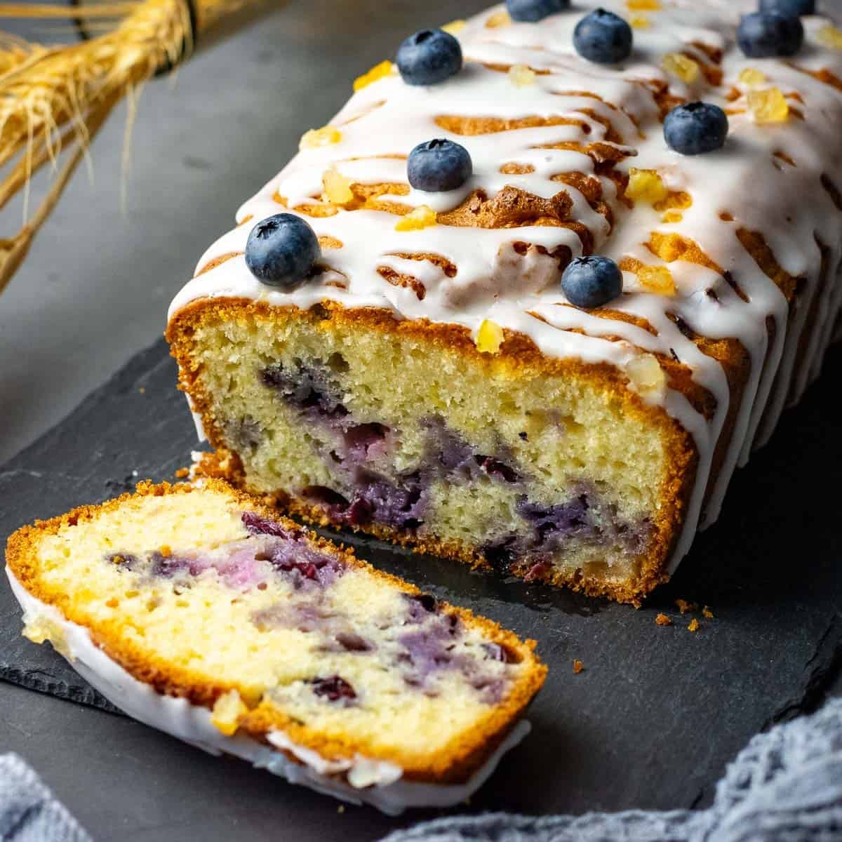 Lemon Blueberry Sourdough Cake on a black slate board with one slice already cut.