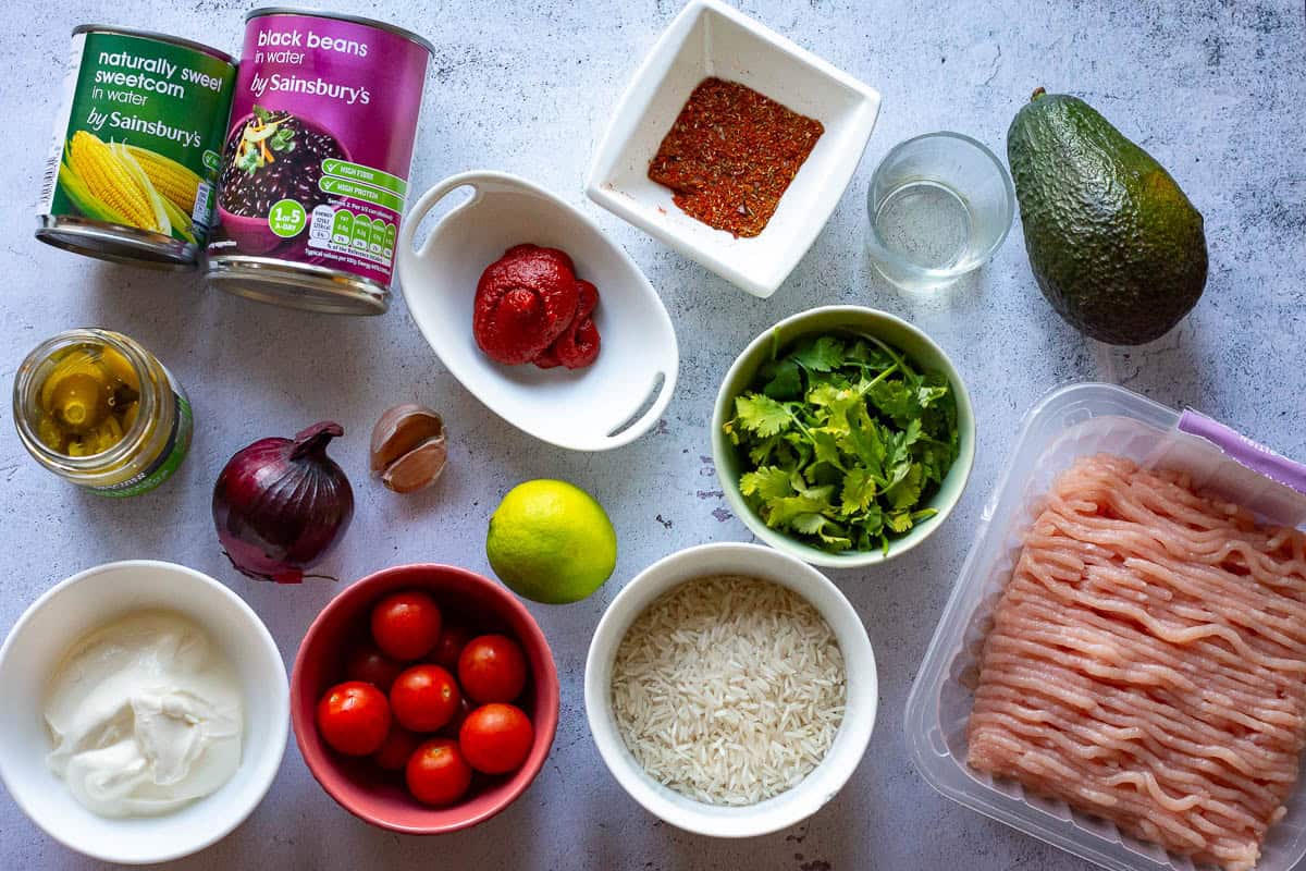 Ingredients for turkey burrito bowl on a light grey surface.