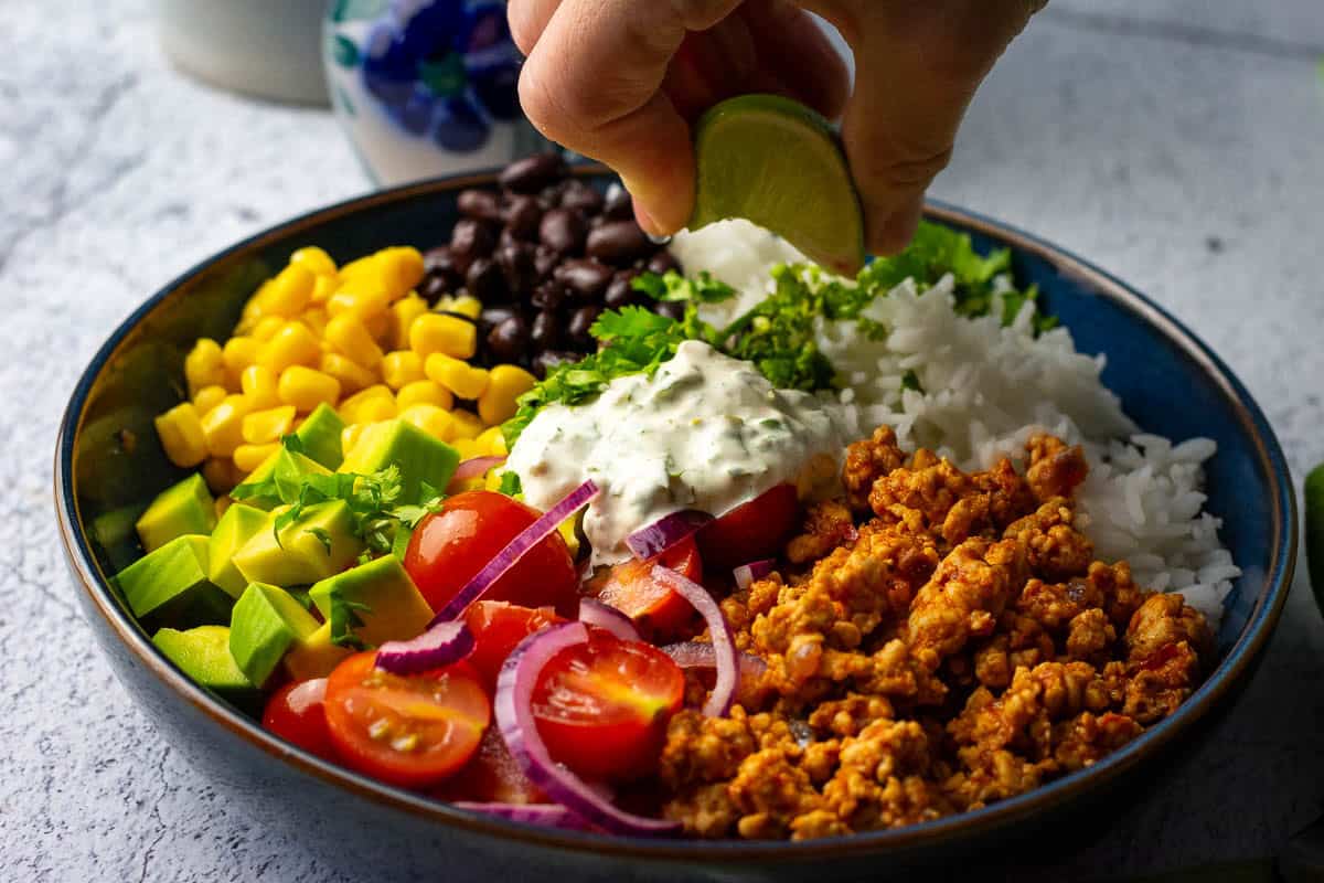 Squeezing lime wedge over the ground turkey burrito bowls.