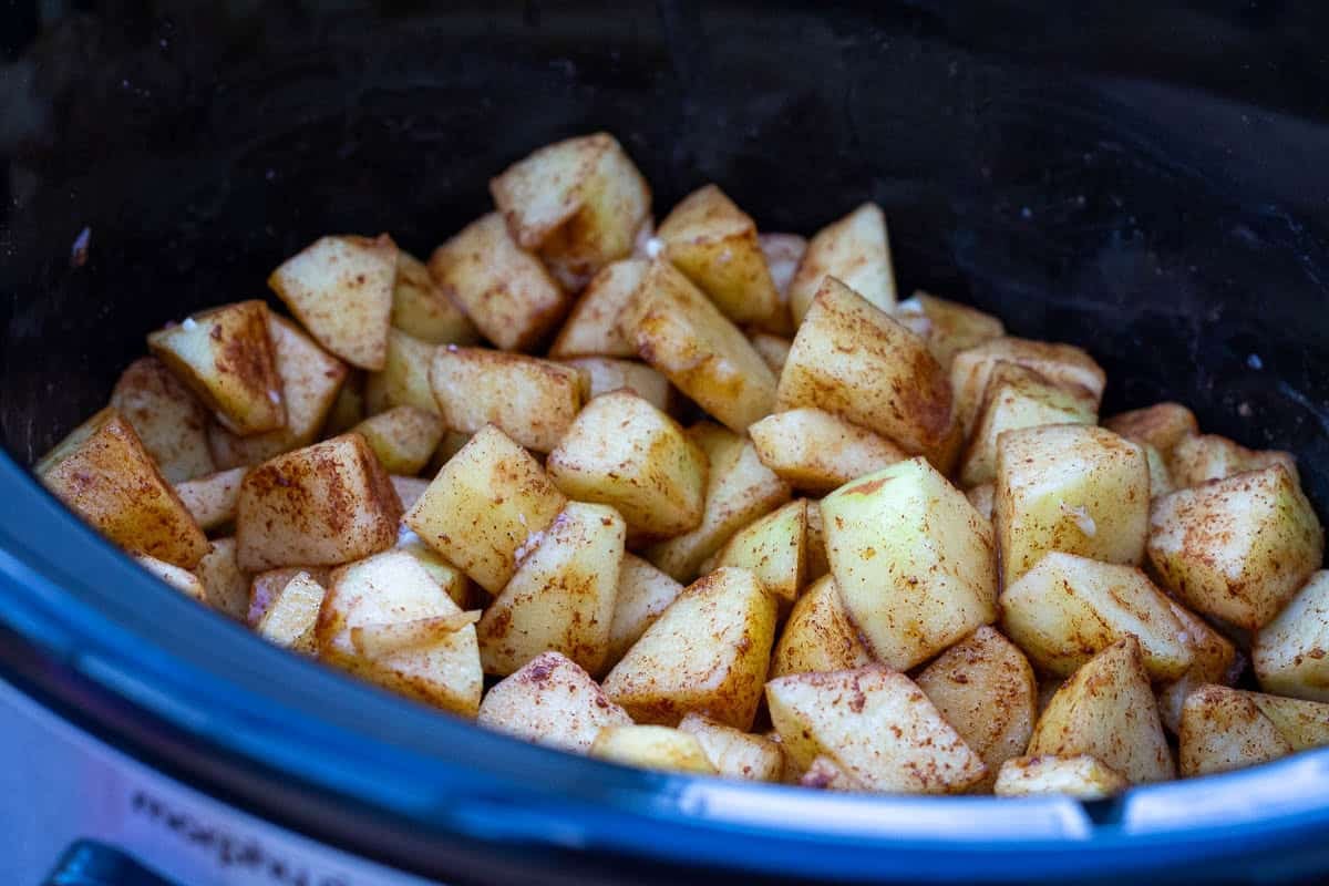 Apples, sugar and cinnamon in a slow cooker bowl.