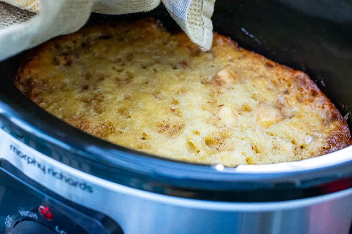 Soft and cakey sourdough cobbler topping in a slow cover set over the apples.