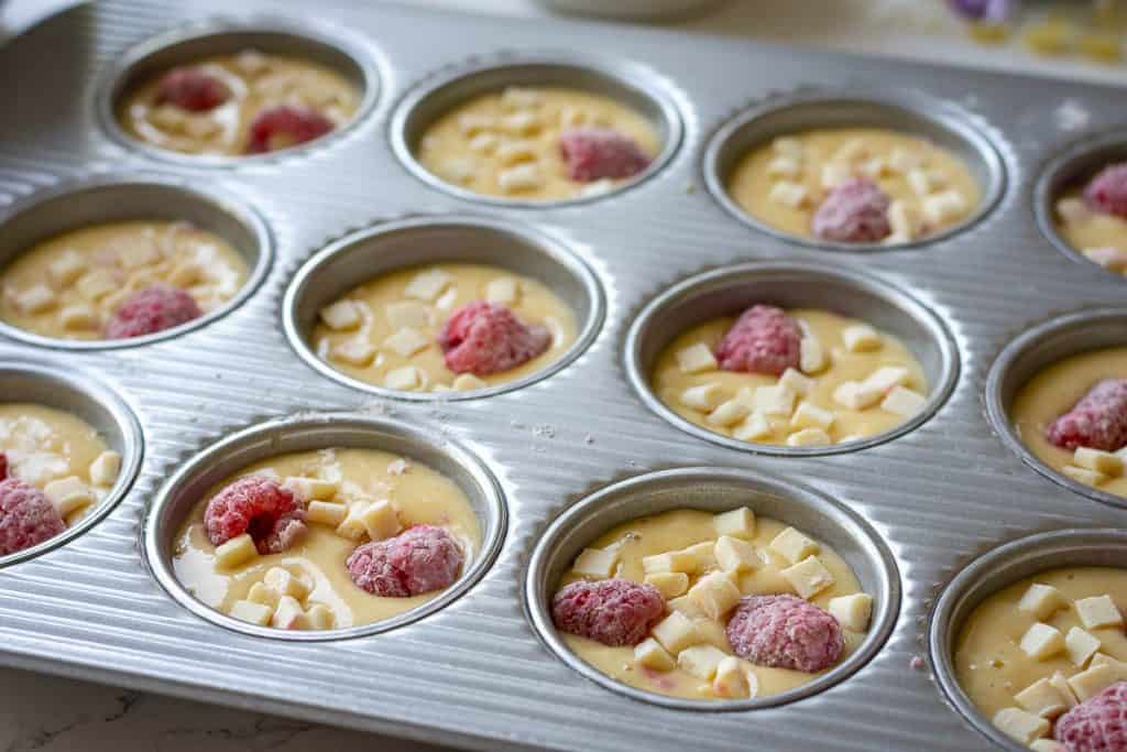 A 12-hole muffin pan filled with sourdough discard muffin batter.