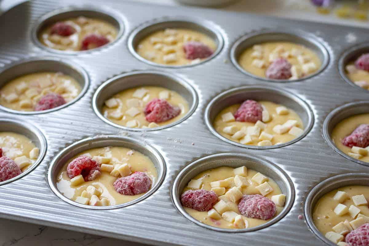 A 12-hole muffin pan filled with sourdough discard muffin batter.