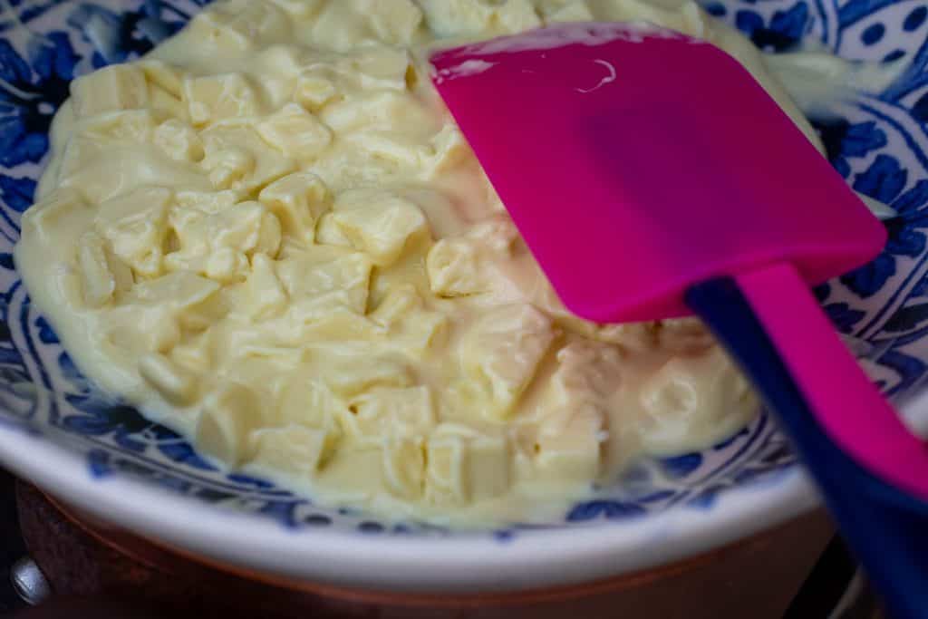 Melting white chocolate in a bowl over simmering water.