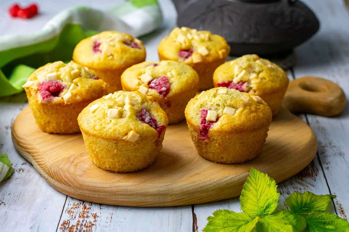 Raspberry and white chocolate sourdough muffins arranged on a wooden board.