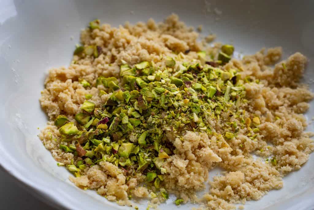 Pistachio streusel topping being mixed in a white bowl.